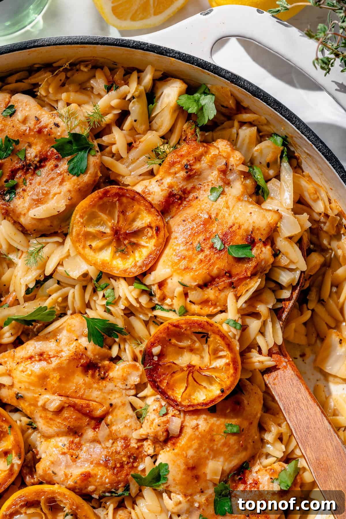 Zesty Lemon Chicken and Orzo 2 Juicy roasted chicken thighs with lemon and orzo pasta, garnished with fresh herbs, ready to be served from a skillet.