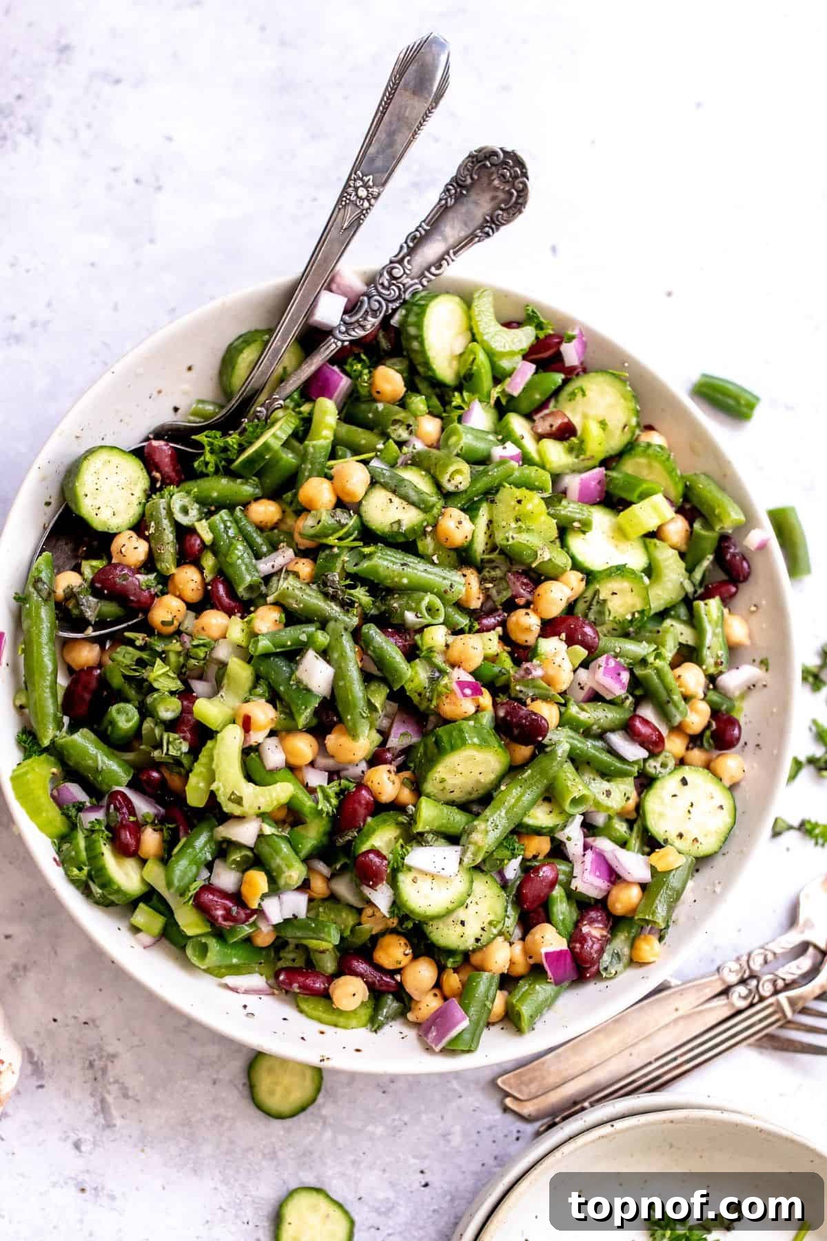 Vibrant Miso Three Bean Salad 2 A beautifully presented three bean salad in a white serving dish with silver serving spoons, ready to be enjoyed.