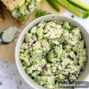 White ceramic bowl with Green Goddess Chicken Salad in it and dressing on the side with bread.