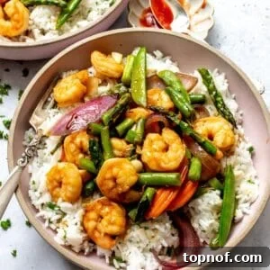 Garlic shrimp stir fry served over white rice in pink bowls with forks to the side. A delicious and healthy family meal.