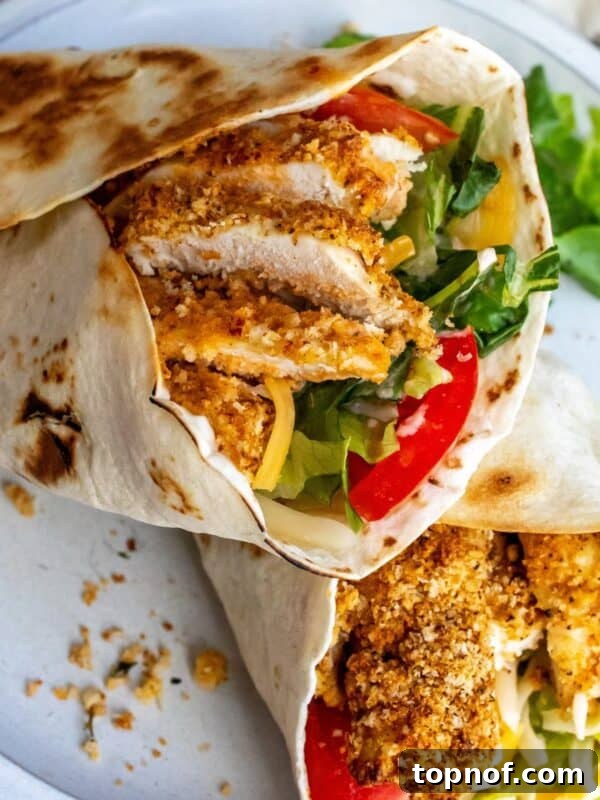 Citrus Tequila-Lime Chicken Recipe for Grilled Weeknight Meals 9 Crispy Chicken Wraps on a white plate with lettuce and tomato.