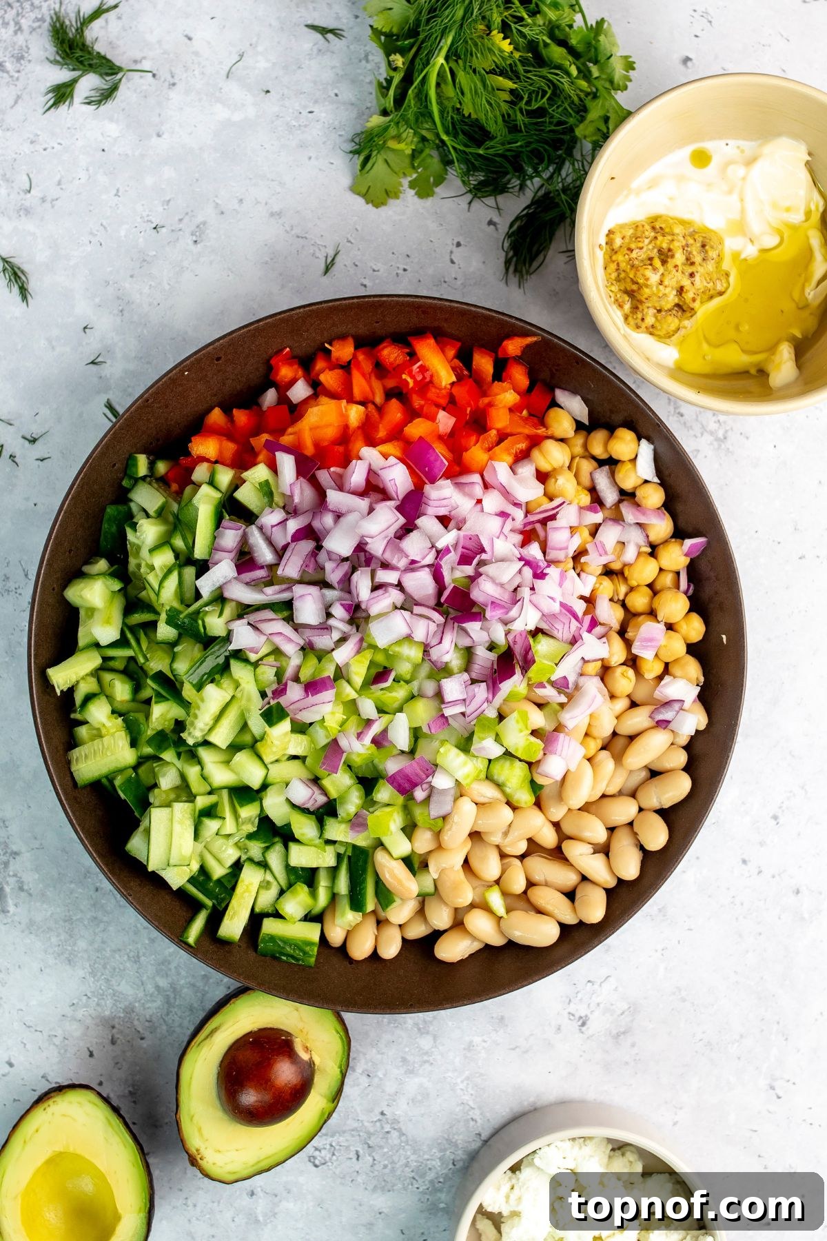 Brown bowl filled to the brim with fresh veggies and beans.