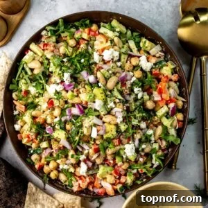 Brown ceramic bowl full of white bean salad with dressing to the side and chips for dipping.