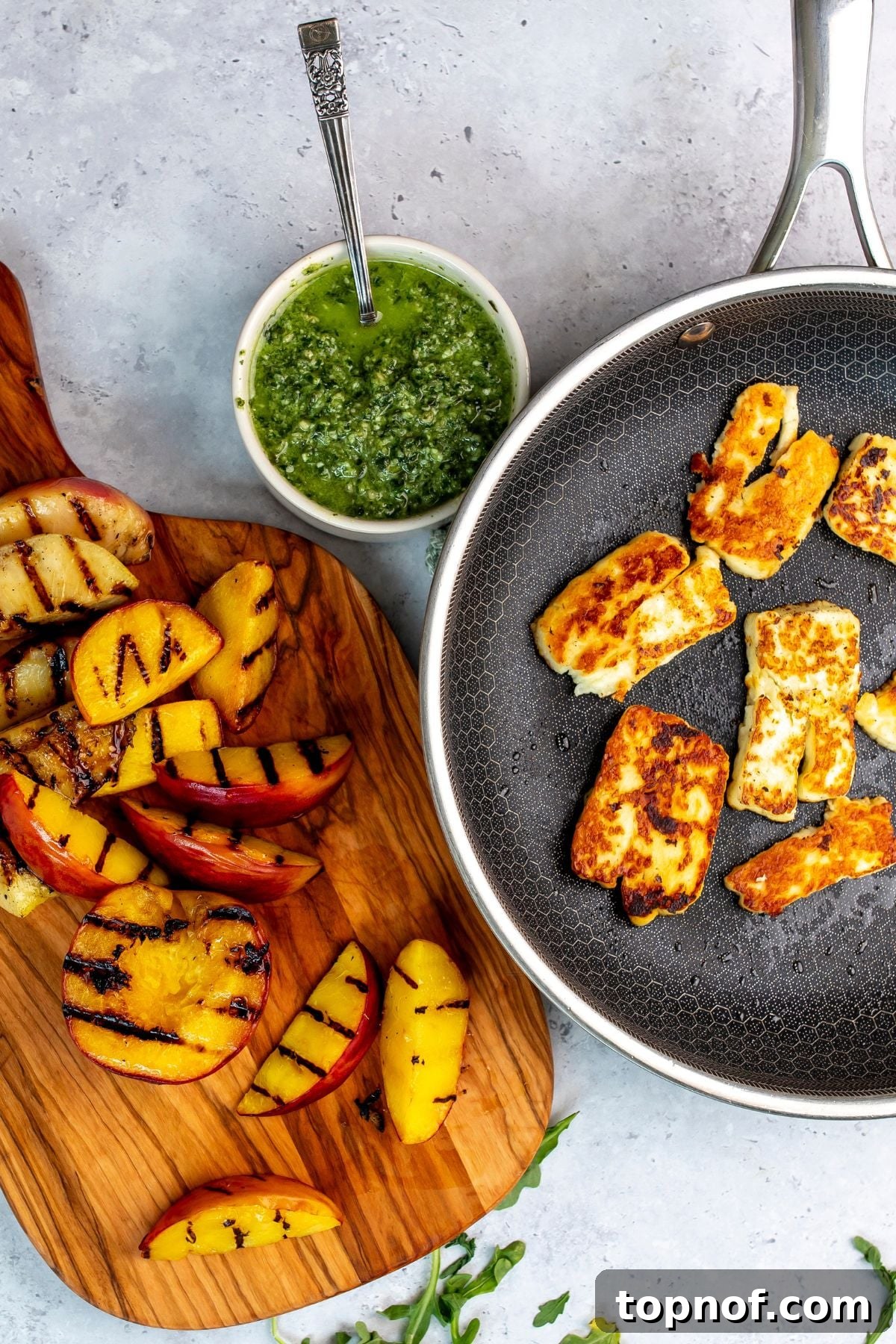 Grilled Peach and Halloumi Salad with Mint and Almonds 4 wood cutting board with peaches on it and arugula to the side.