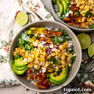 Street Corn Chicken Rice Bowls with Lime Crema 11 Two Chicken Street Corn Rice Bowls on a counter with a floral napkin underneath and silver forks to the side.