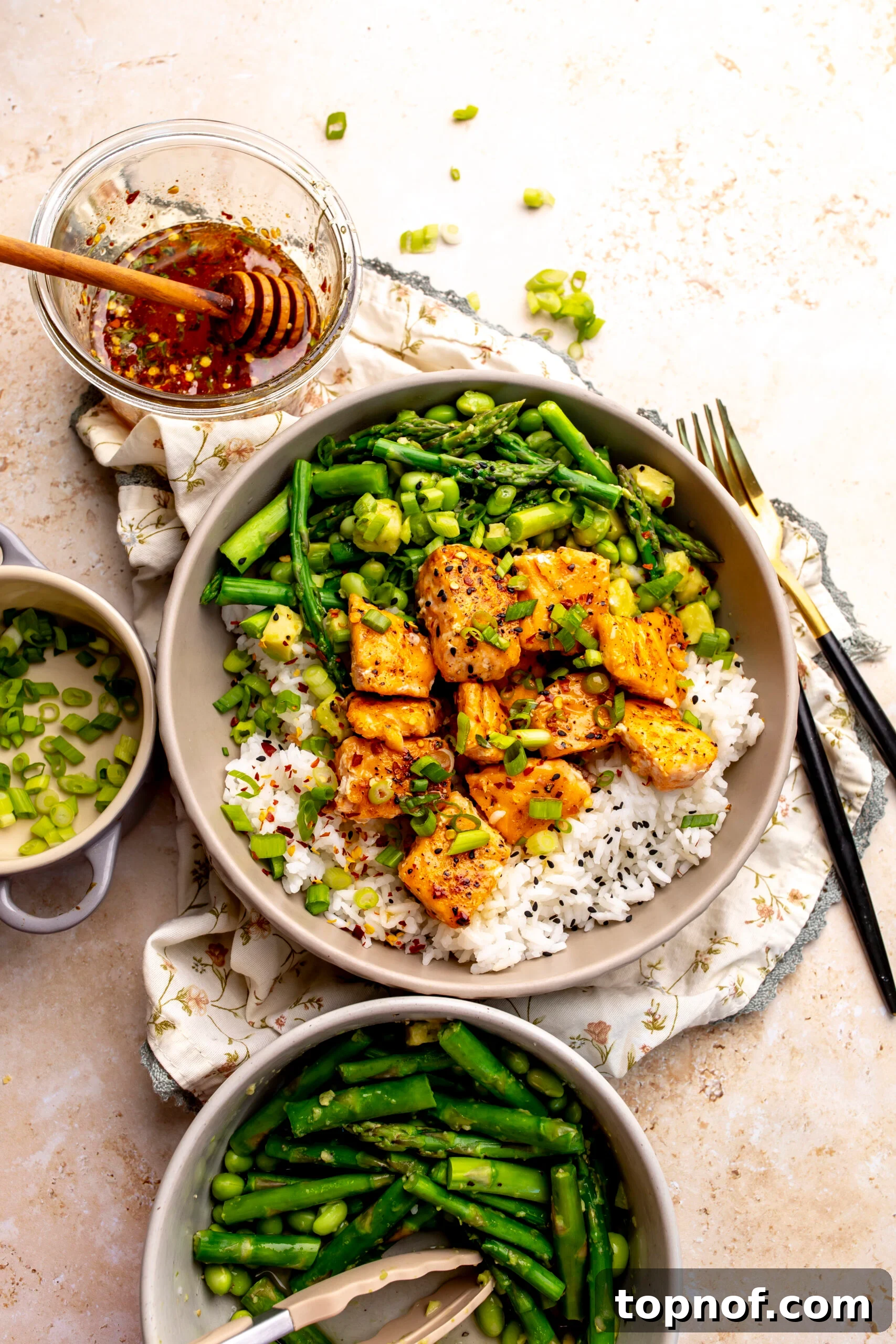 Hot Honey-Glazed Salmon with Crispy Skin 2 Ceramic bowl with hot honey salmon bites over rice with crispy asparagus and avocado.