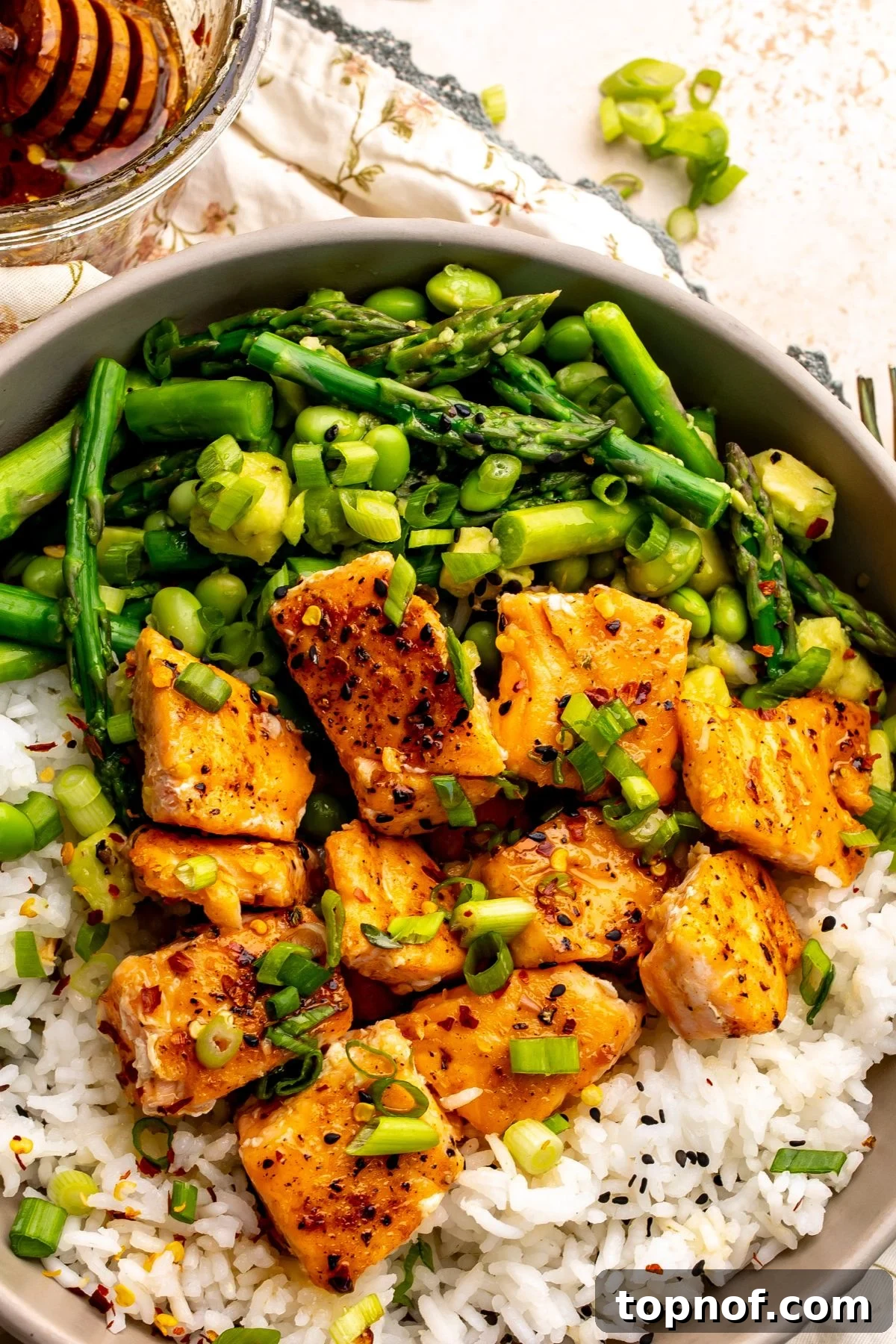 Hot Honey-Glazed Salmon with Crispy Skin 6 Hot Honey Salmon up close served over rice with veggies and green onions.