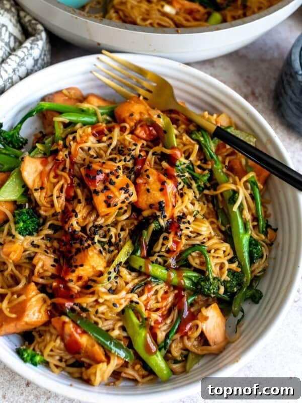 Hot Honey-Glazed Salmon with Crispy Skin 10 Teriyaki Salmon noodles in a white bowl with a black fork in the bowl.