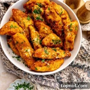 Golden Garlic Parmesan Chicken Strips in a white bowl topped with parsley.