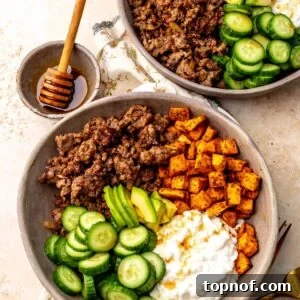 Two hot honey ground beef bowls on a countertop with a small bowl of hot honey on the countertop next to the bowls.