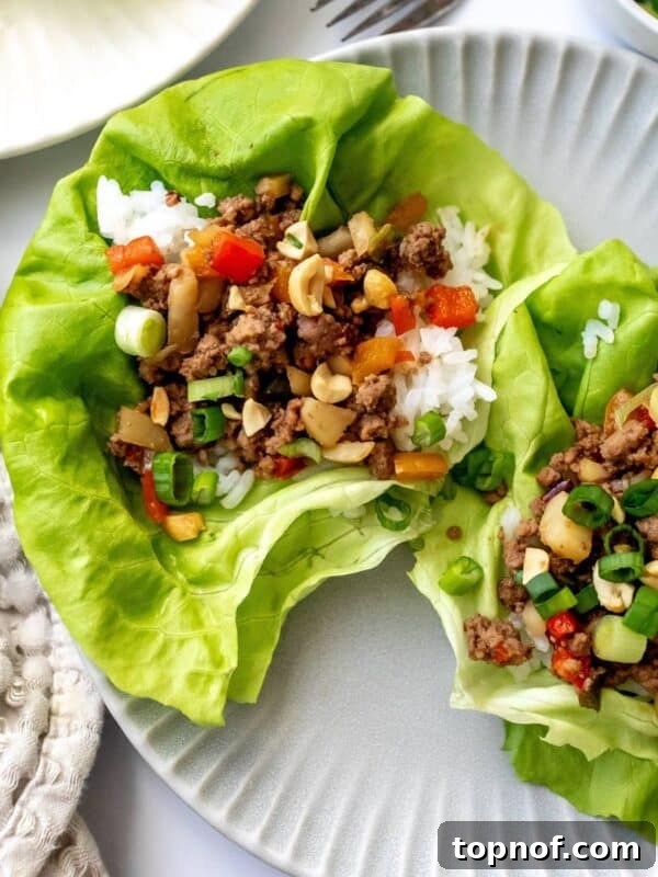 Ground Beef Lettuce Wraps on grey plates with a fork and onions on the side.