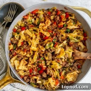 Dirty cabbage in a grey pan with a wooden spoon and a towel to the side.