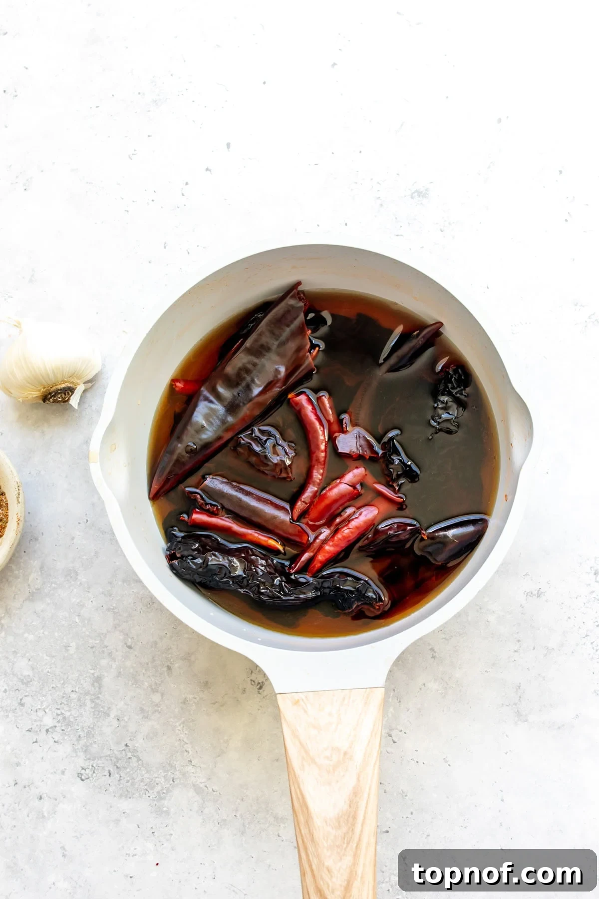 Slow Cooker Beef Birria Tacos with Dipping Consomme 4 The chiles soaking in hot water in a saucepan.