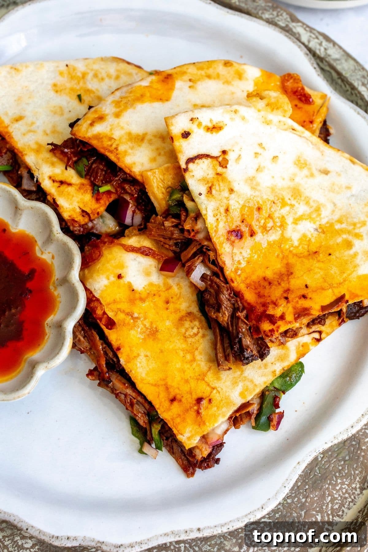 Birria Quesadillas with Dipping Consomme 6 The four slices of birria quesadilla on a white plate for serving.