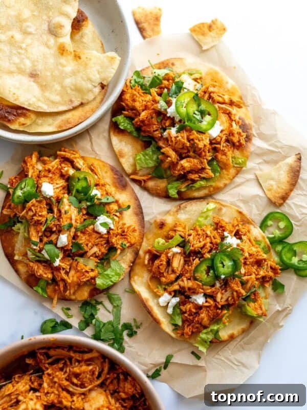 Chicken Tinga Toastadas on a white counter on parchment paper with jalapeños.