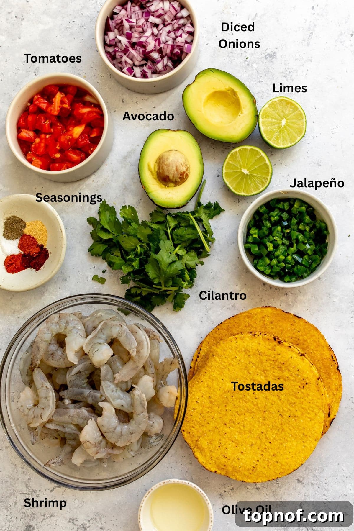 All of the ingredients for shrimp tostadas in bowls on a countertop.