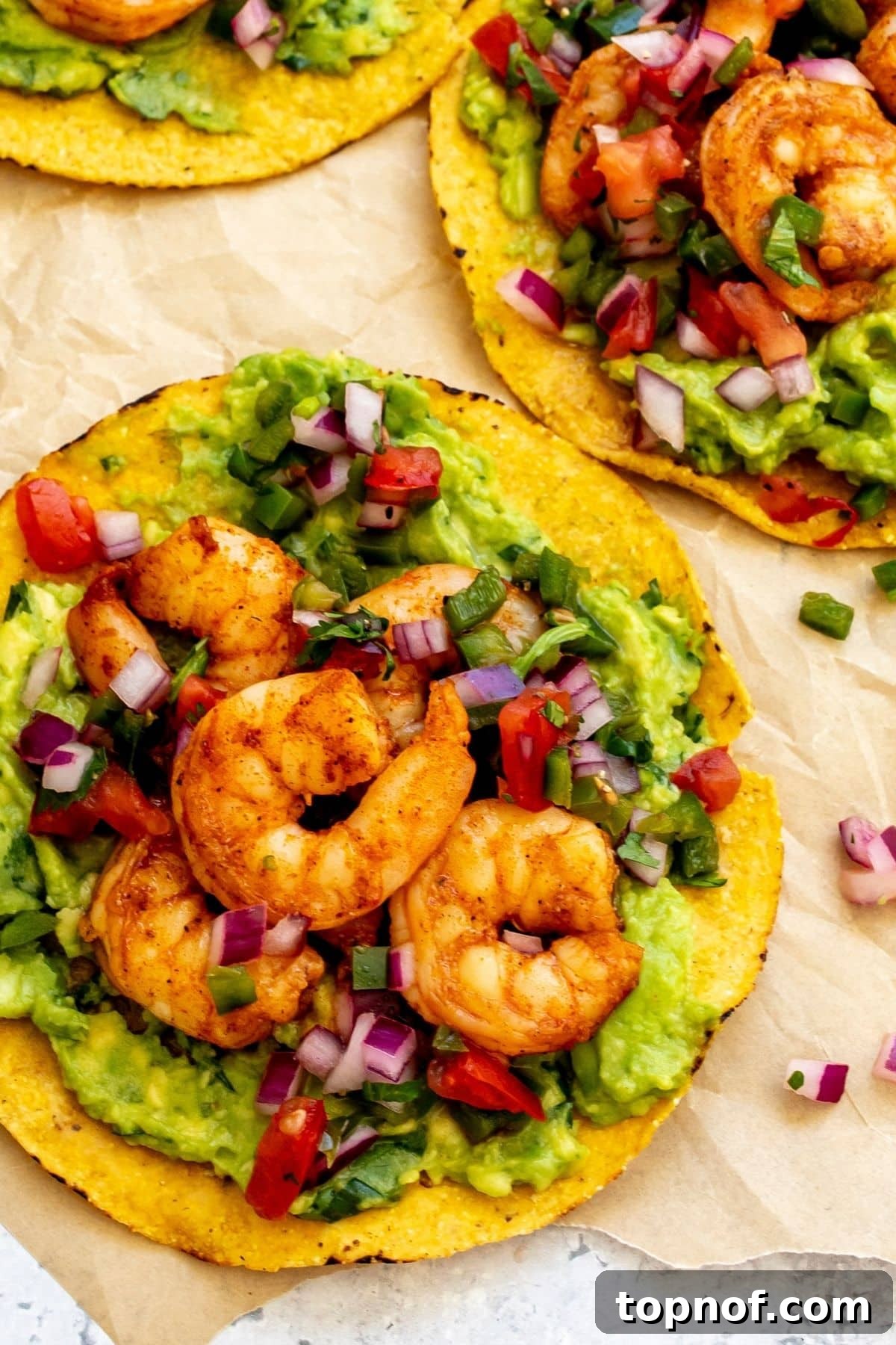 A shrimp tostada layered with guacamole, shrimp, and pico.